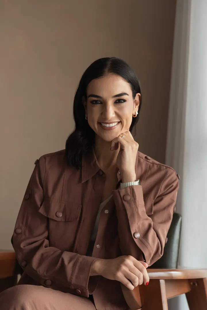 Dra. Luciana Paschoal, geriatra, sorrindo com a mão no queixo